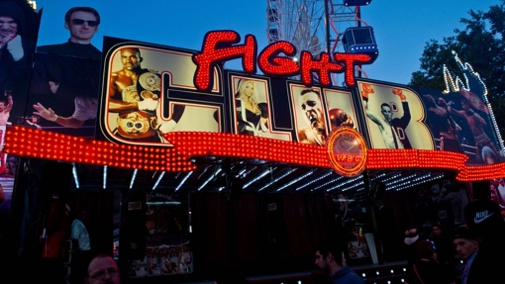 Boxbude bei Nacht mit leuchtendem Schriftzug und Publikum